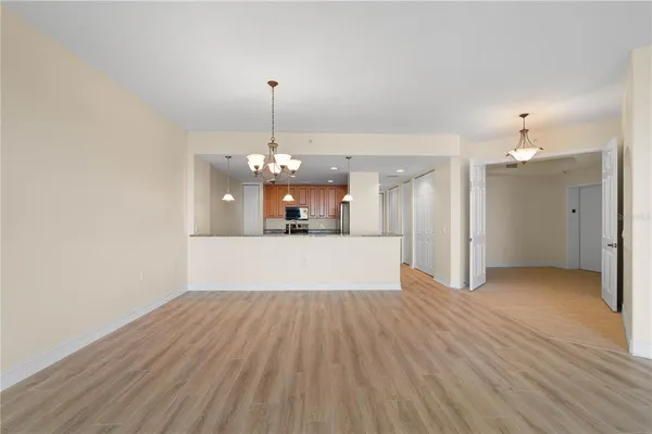 a view of a room with a chandelier fan and wooden floor