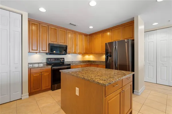 a kitchen with stainless steel appliances granite countertop a refrigerator a stove a sink a microwave and island