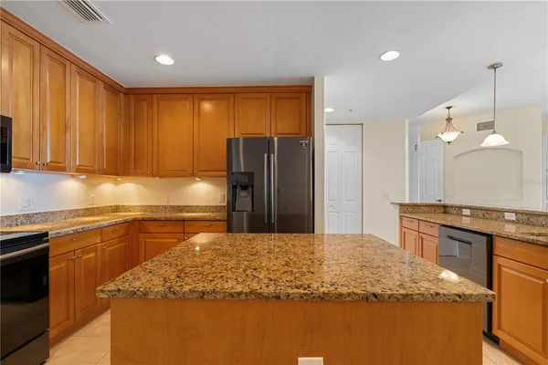 a kitchen with kitchen island granite countertop a stove top oven a sink dishwasher a refrigerator and cabinets with wooden floor
