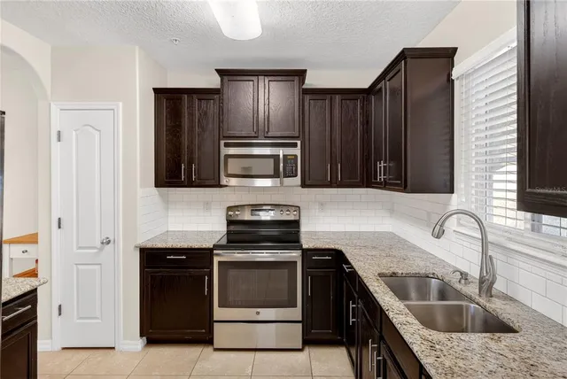 a kitchen with granite countertop wooden cabinets a stove top oven and stainless steel appliances