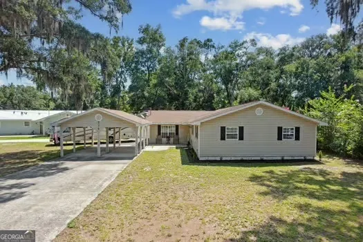a view of a house with a yard and large trees