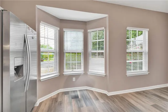 a view of an empty room with wooden floor and windows