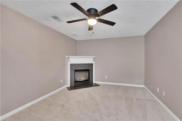 an empty room with a ceiling fan and a fireplace