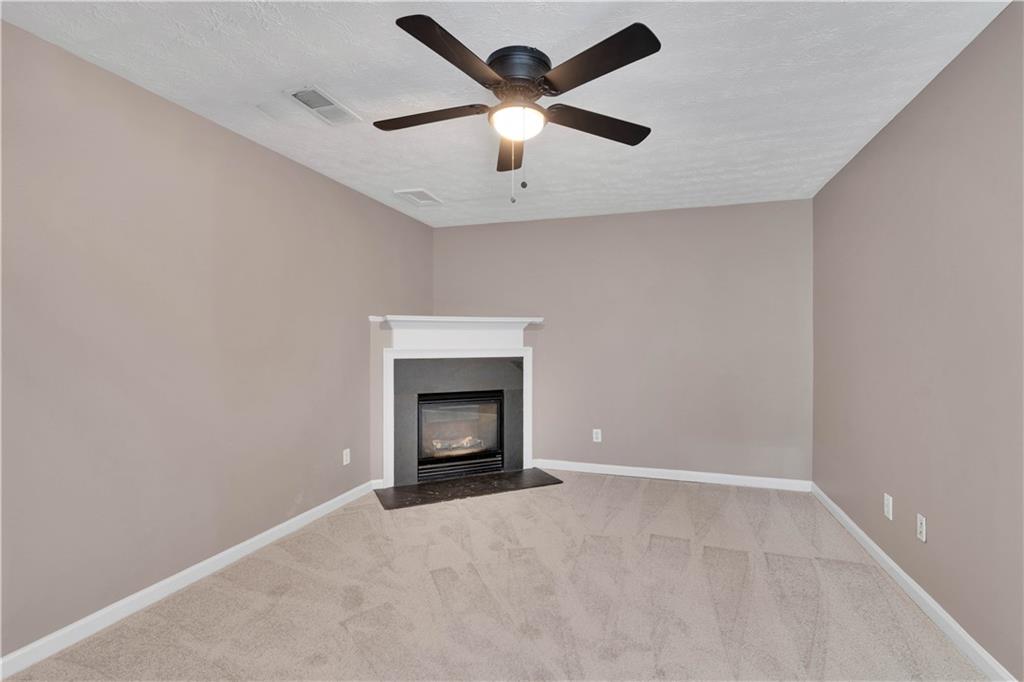 4005 Spring Cove Drive Duluth, GA 30097 - Photo 8 of 23 an empty room with a ceiling fan and a fireplace