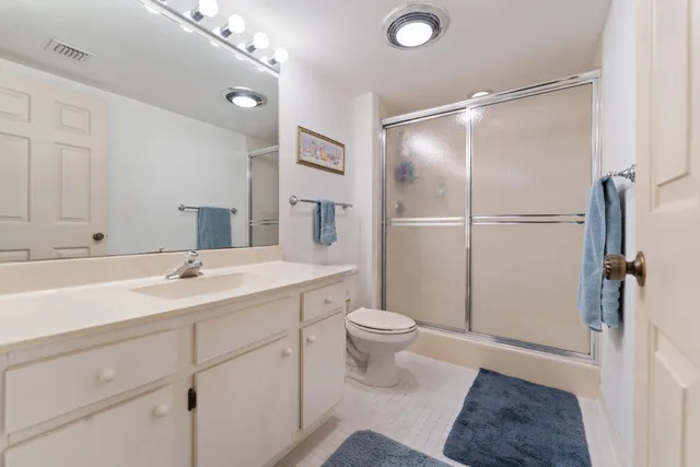 a bathroom with a sink a toilet a mirror and shower