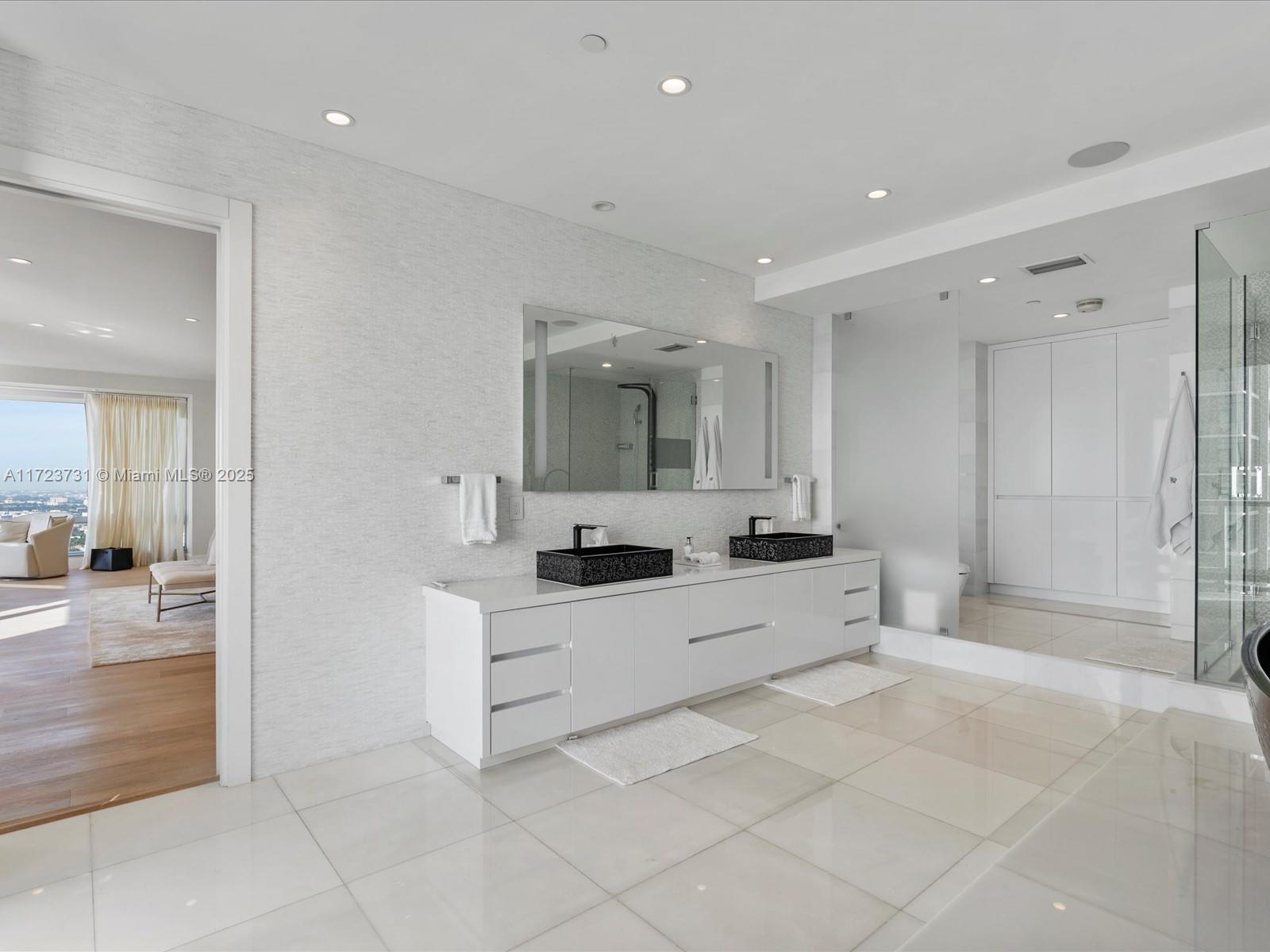 1425 Brickell Avenue, Unit 52BC Miami, FL 33131 - Photo 34 of 72 a large white bathroom with a granite countertop sink mirror and bathtub