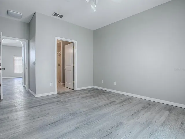 a view of an empty room with wooden floor and closet