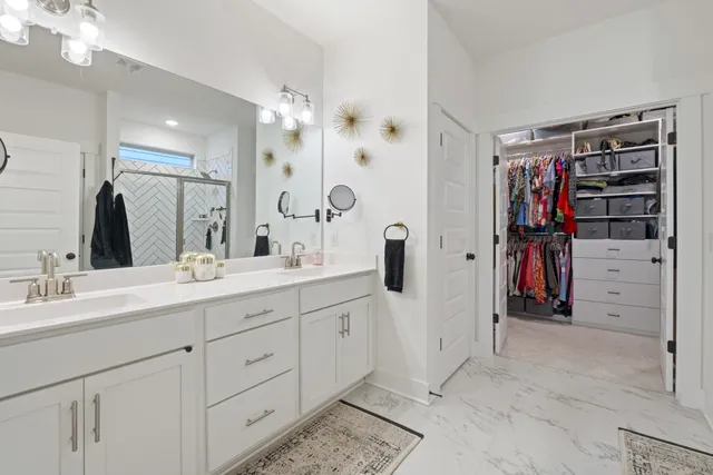 a bathroom with a double vanity sink a toilet a shower and a mirror