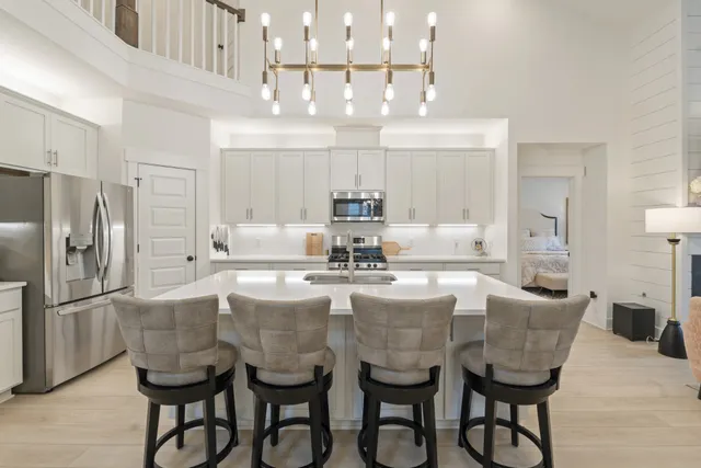 a kitchen with stainless steel appliances kitchen island granite countertop a dining table chairs and a refrigerator