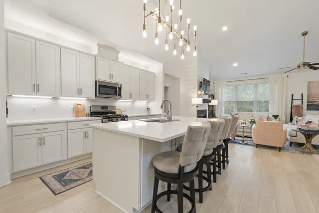 a kitchen that has a lot of white cabinets and stainless steel appliances