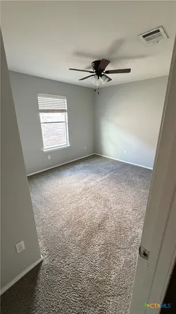 en empty room with windows and ceiling fan