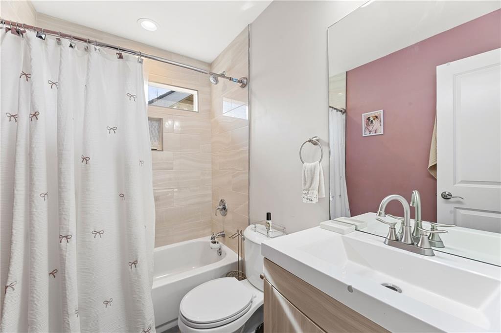 221 Laurel Avenue Southwest Atlanta, GA 30314 - Photo 23 of 29 a bathroom with a sink a toilet a mirror a bathtub and shower
