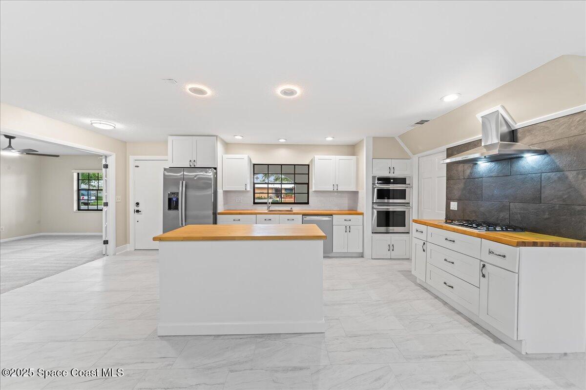 2010 Talloak Road Melbourne, FL 32935 - Photo 5 of 45 a large white kitchen with stainless steel appliances kitchen island granite countertop a large counter top and a stove top oven