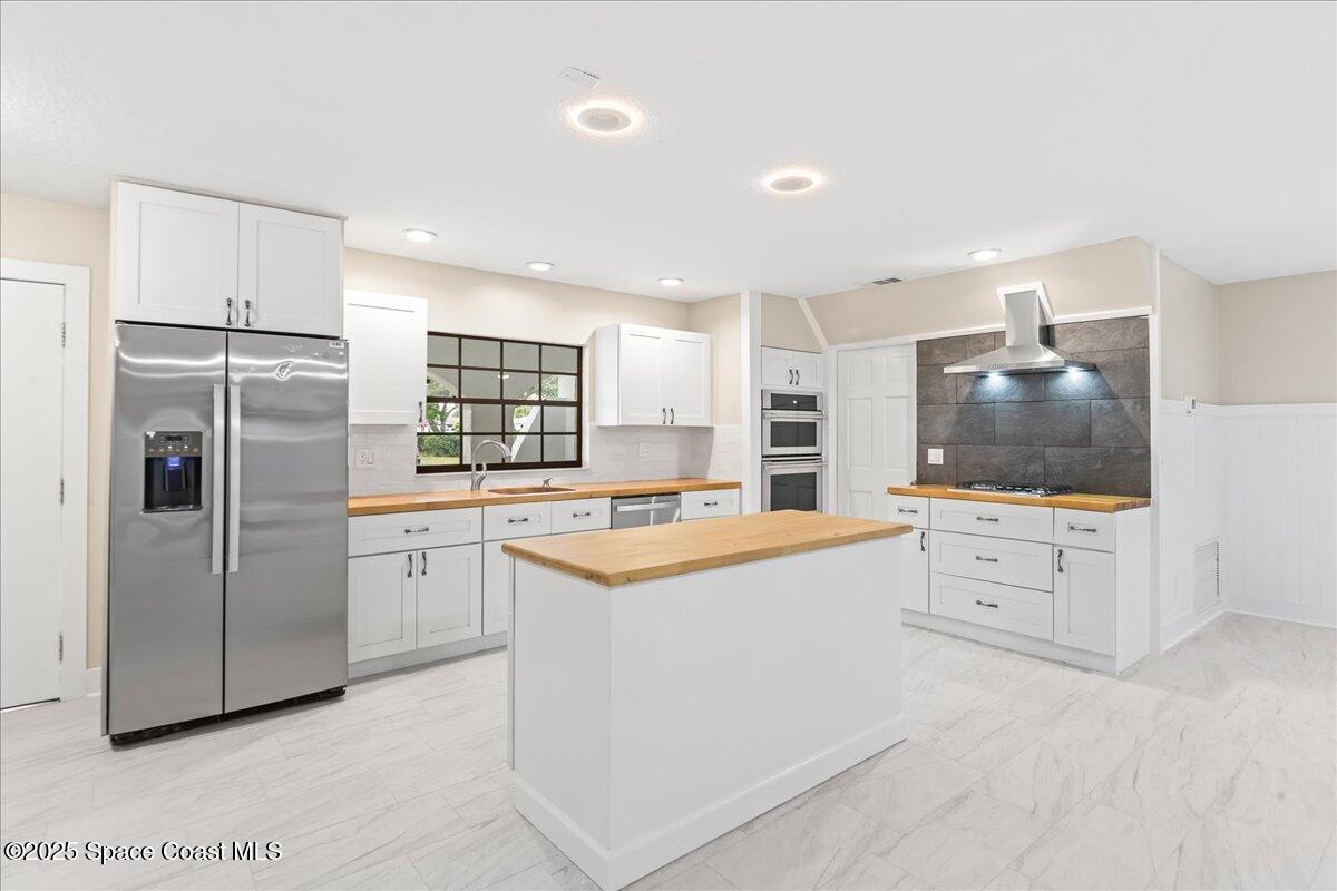 2010 Talloak Road Melbourne, FL 32935 - Photo 9 of 45 a kitchen with white cabinets and stainless steel appliances