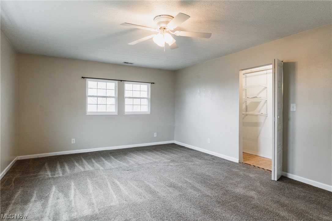 2815 Sealy Ridge Road Vincent, OH 45784 - Photo 10 of 21 Unfurnished bedroom featuring a closet, a textured ceiling, dark colored carpet, a walk in closet, and ceiling fan