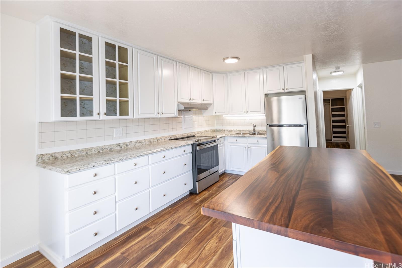 a kitchen with stainless steel appliances granite countertop a stove a sink and white cabinets with wooden floor