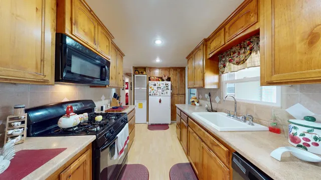 a kitchen with stainless steel appliances a stove a sink dishwasher and cabinets with wooden floor