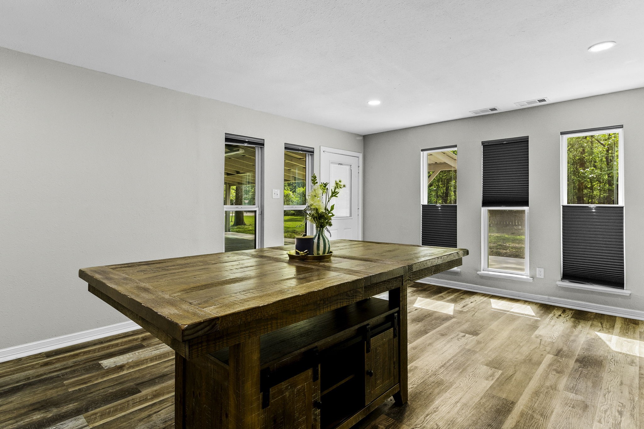 21 Red Oak Circle Point Blank, TX 77364 - Photo 6 of 32 This room features a spacious, light-filled area with large windows and modern blinds. A rustic wooden table adds warmth, and the hardwood floors enhance the inviting atmosphere.