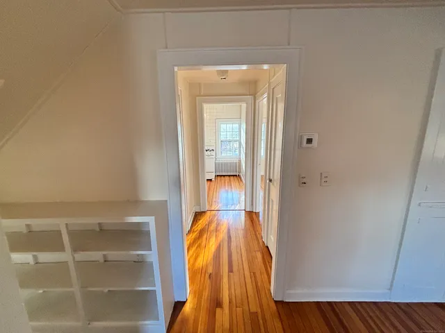 a view of a hallway with wooden floor and a bathroom