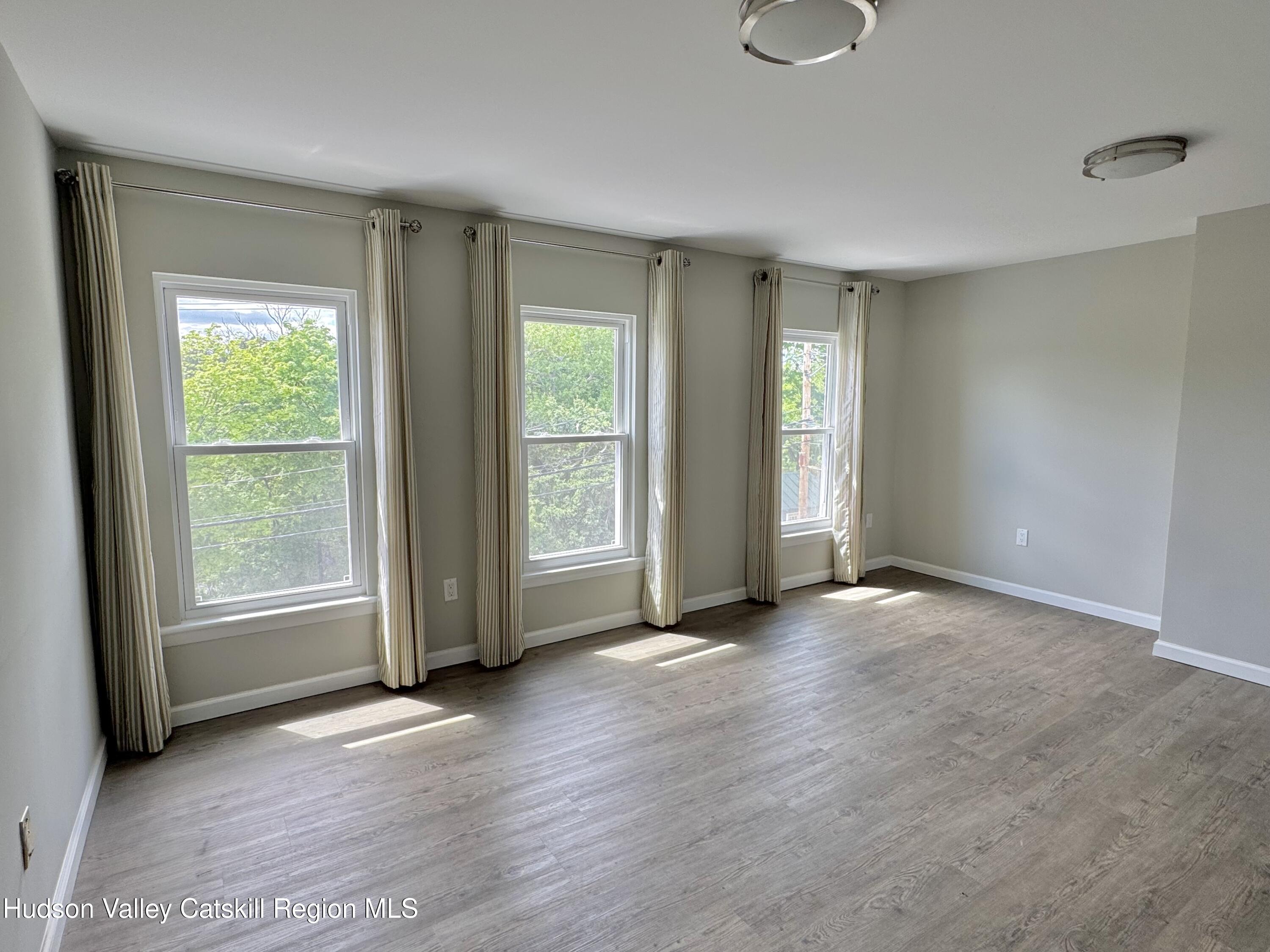 218 Water Street, Unit 5 Catskill, NY 12414 - Photo 6 of 12 an empty room with wooden floor and windows