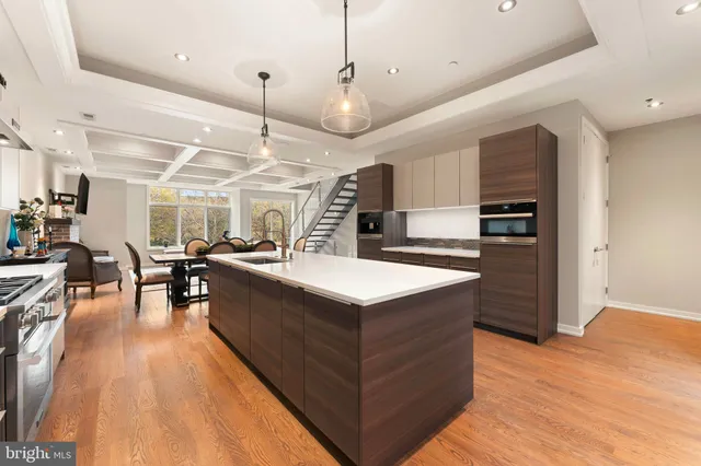 a kitchen with stainless steel appliances granite countertop a large kitchen island a stove a refrigerator a sink and a dining table with wooden floor