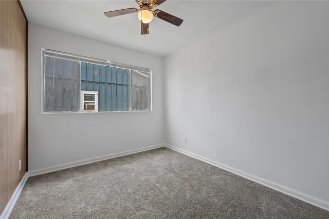 an empty room with a chandelier fan and windows
