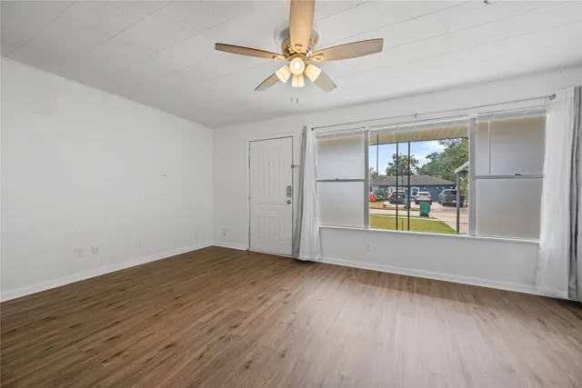 an empty room with wooden floor and windows