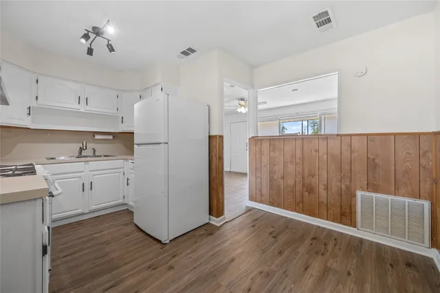 a kitchen with wooden floors and white cabinets