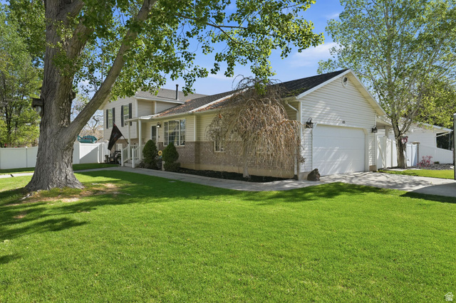 415 East 400 North Santaquin, UT 84655 - Photo 3 of 39 Residential property featuring a two-car garage with a white door, light-colored siding, and a stone facade detail