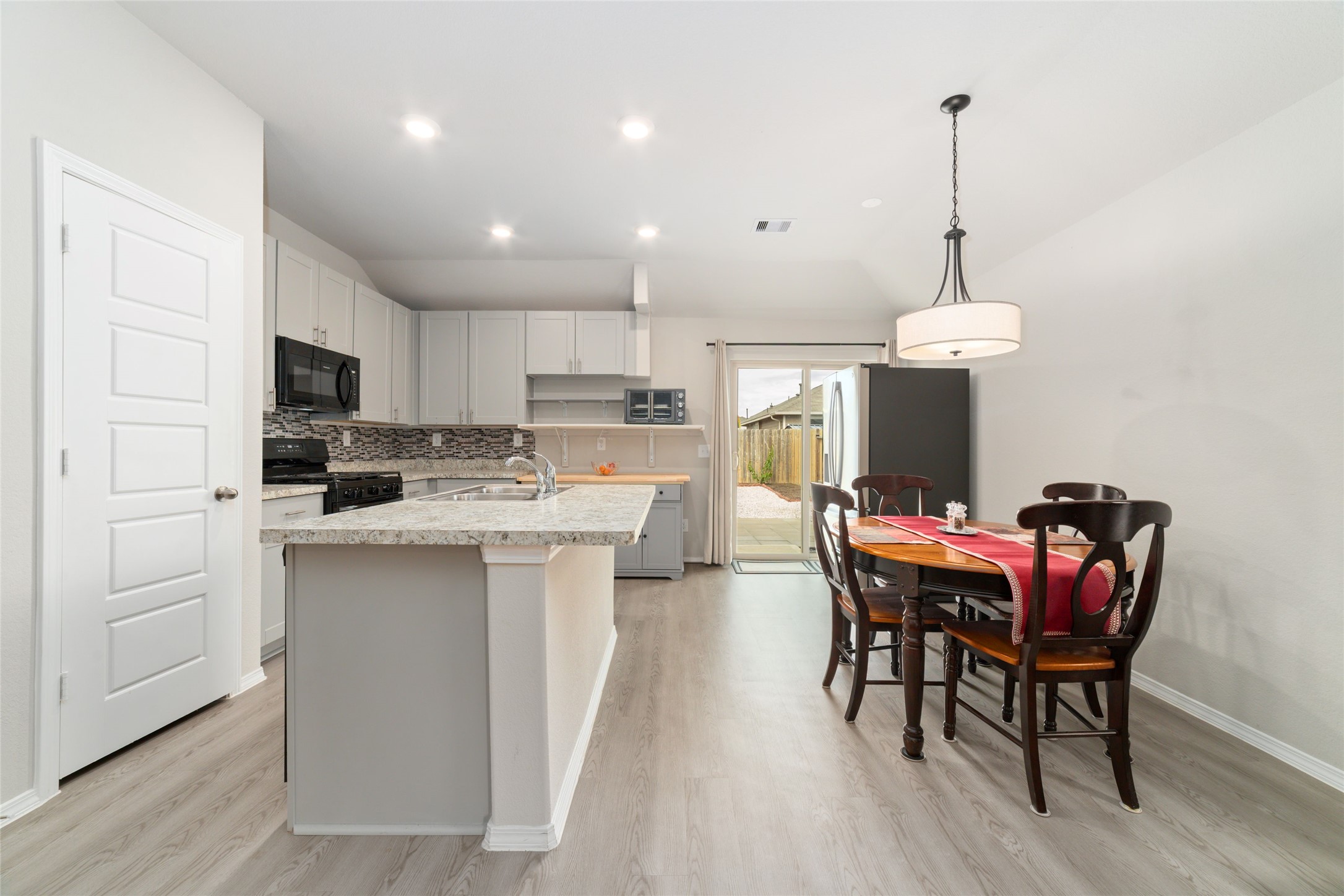 14232 Shasta Ridge Drive Conroe, TX 77303 - Photo 7 of 26 Light-filled kitchen and dining area with high ceilings and recessed lighting, offering an open layout that extends to the backyard through sliding glass doors.