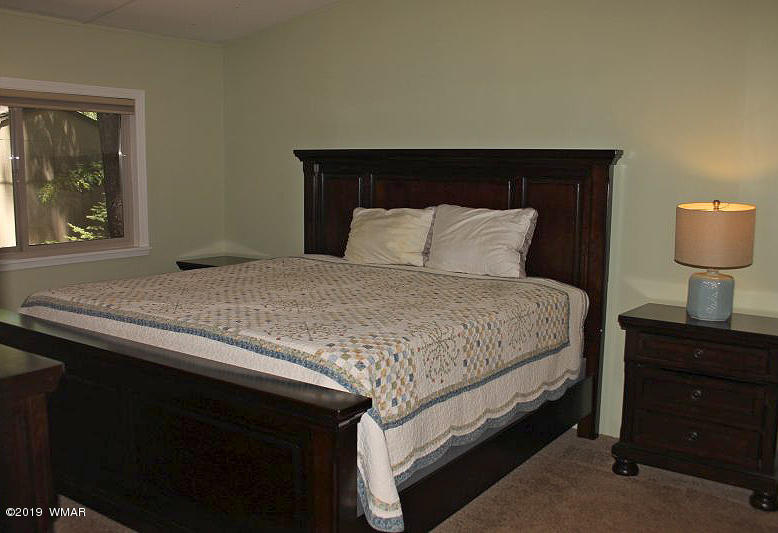 5472 North Blue Ridge Loop Pinetop, AZ 85935 - Photo 11 of 22 a bedroom with a bed and a lamp on table