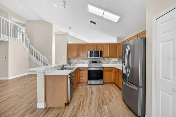 a kitchen with a refrigerator a sink dishwasher with a stove and wooden floor