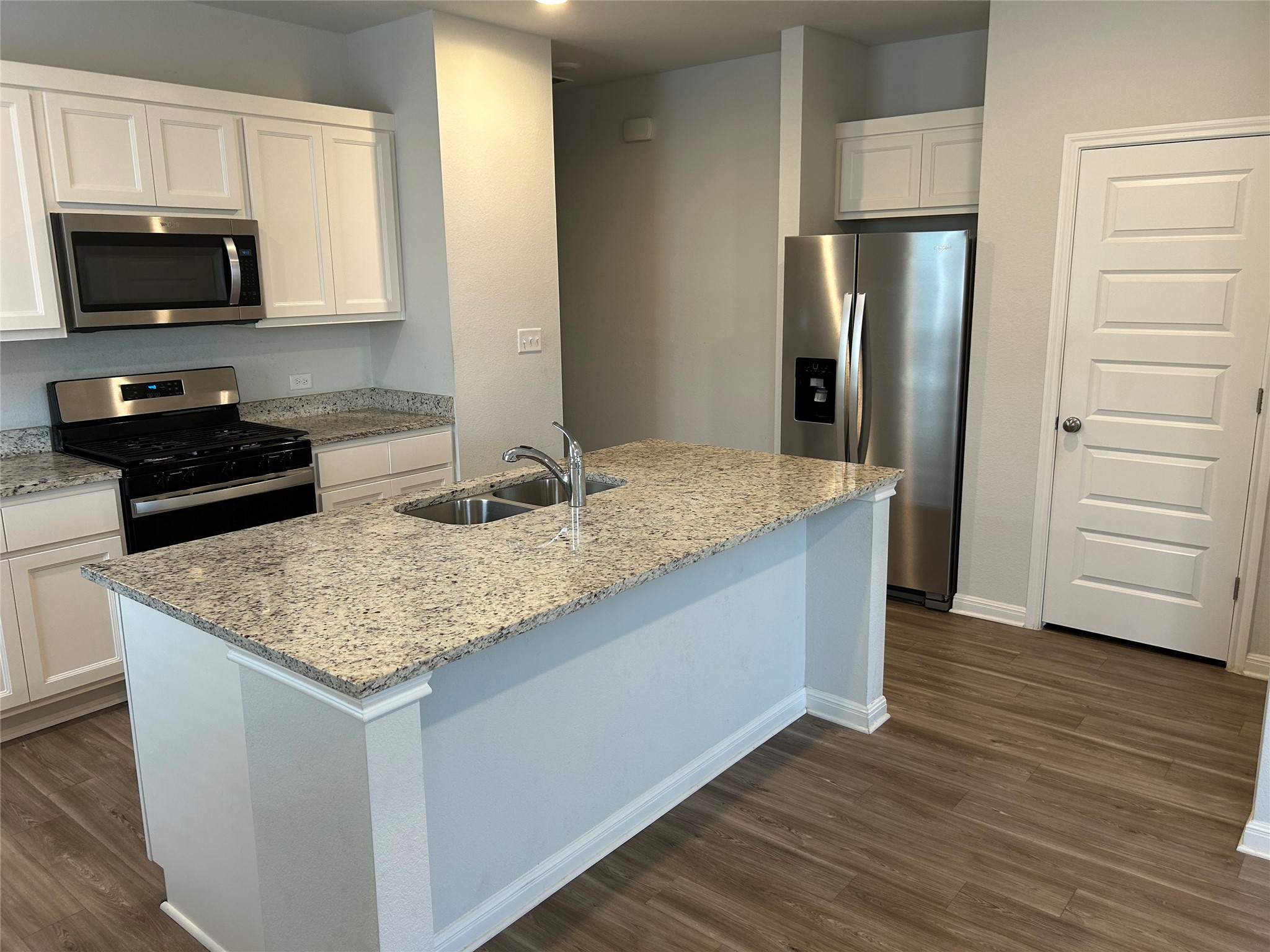 Polished stone countertops pair beautifully with crisp white cabinetry and durable wood-look flooring.