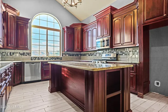 a kitchen with stainless steel appliances granite countertop a sink a stove and cabinets