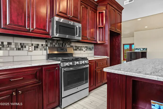 a kitchen with stainless steel appliances granite countertop a kitchen island a cabinets a stove and a refrigerator