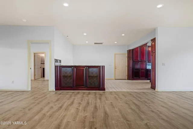 a view of an empty room with wooden floor and window