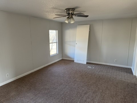 3035 County Road 255 Georgetown, TX 78633 - Photo 20 of 23 Unfurnished bedroom featuring dark colored carpet, ceiling fan, a textured ceiling, and a decorative wall