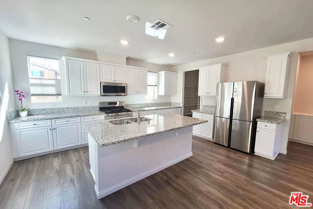 7245 Maple Road Van Nuys, CA 91405 - Photo 1 of 1 a kitchen with stainless steel appliances granite countertop a refrigerator a stove top oven a sink and dishwasher with wooden floor