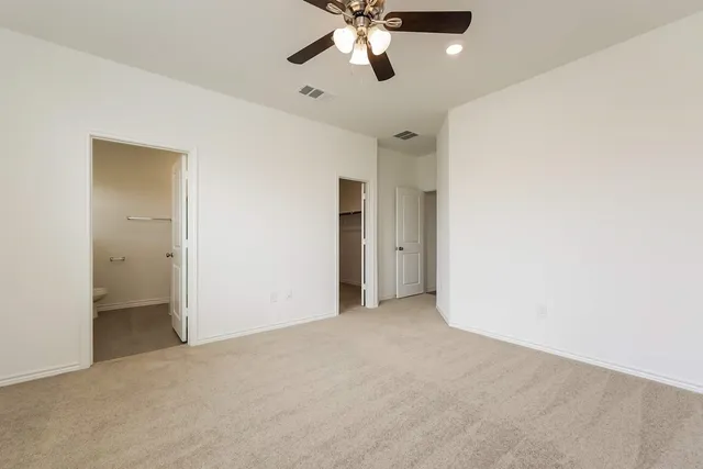 a view of an empty room and chandelier fan