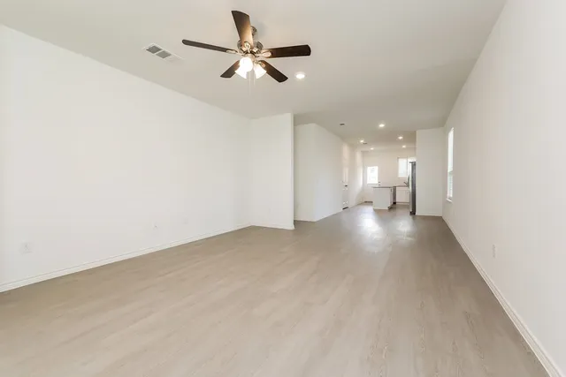 a view of a big room with wooden floor a ceiling fan and windows