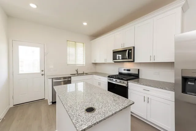 a kitchen with granite countertop white cabinets and stainless steel appliances