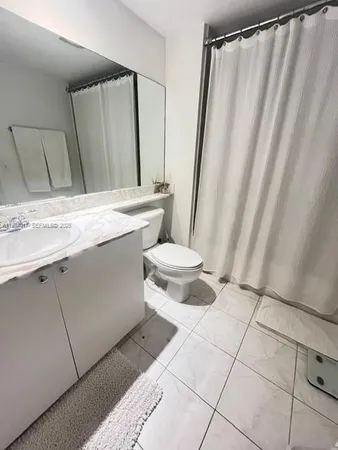 a bathroom with a sink a toilet a mirror and shower curtain