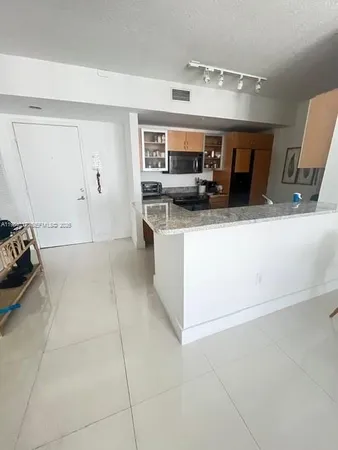 a living room with stainless steel appliances kitchen island granite countertop a sink and cabinets