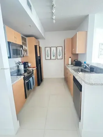 a kitchen with stainless steel appliances granite countertop a refrigerator a stove a sink dishwasher and white cabinets with wooden floor