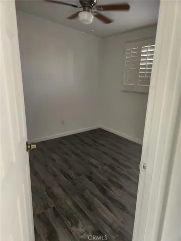 en empty room with wooden floor and fan