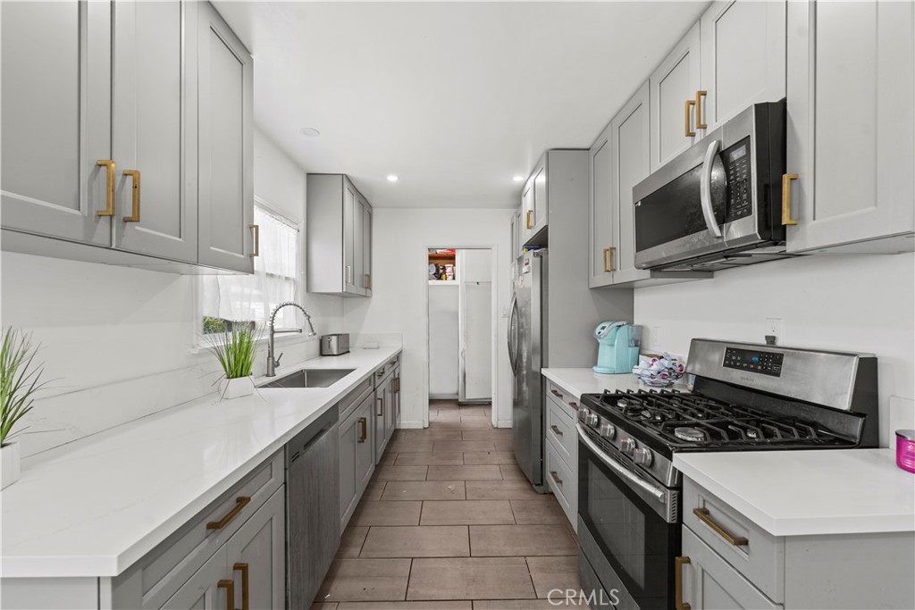 2725 East Tyler Street Carson, CA 90810 - Photo 7 of 30 a kitchen with stainless steel appliances a sink a stove and cabinets