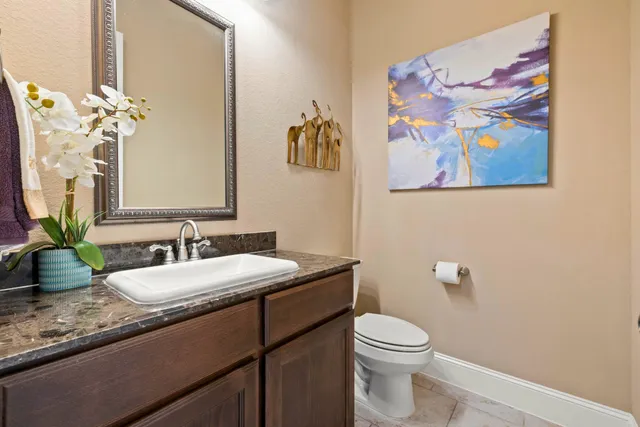 a bathroom with a granite countertop toilet a sink a mirror and vanity