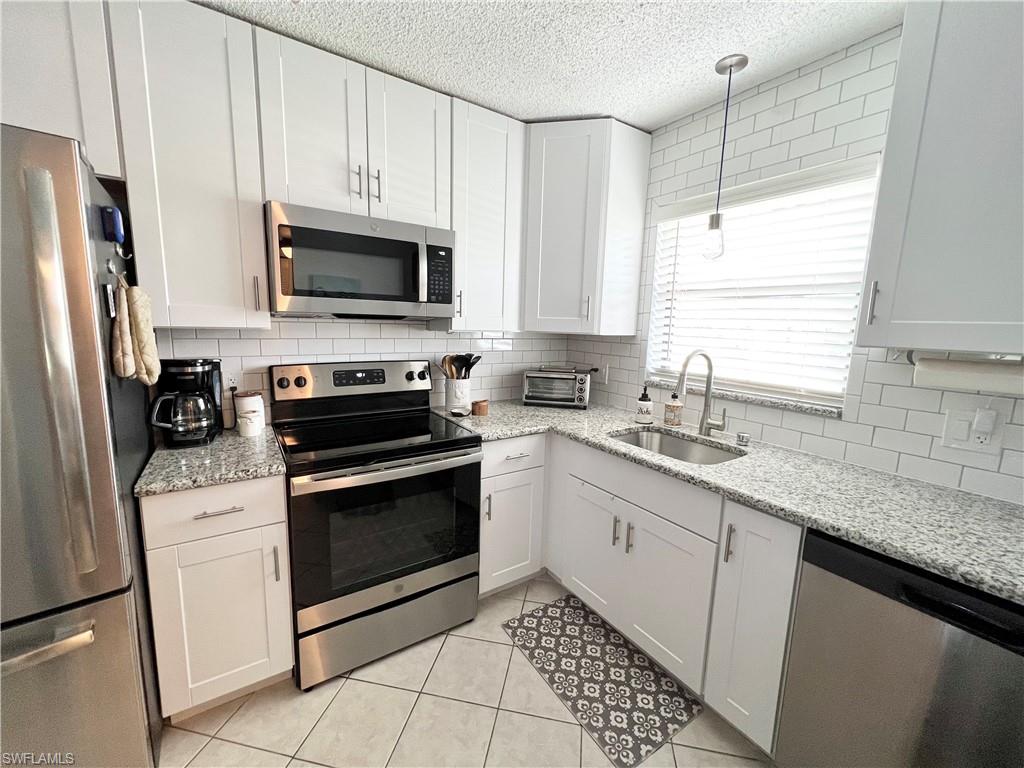 a kitchen with stainless steel appliances granite countertop a sink stove microwave and refrigerator