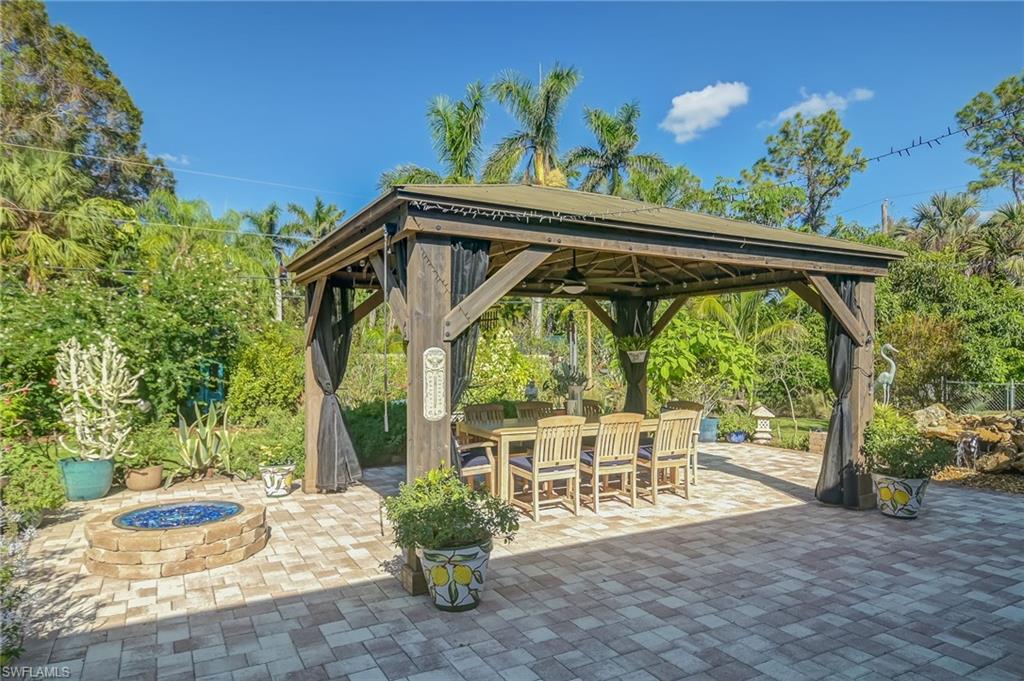 6350 Parkers Hammock Road Naples, FL 34112 - Photo 29 of 49 a view of a patio with table and chairs potted plants and floor to ceiling window