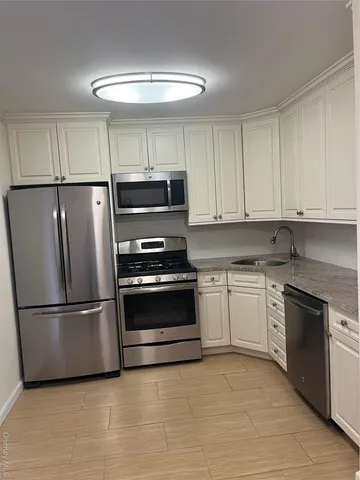 a kitchen with granite countertop a refrigerator and a stove top oven